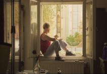 Novinářka Saša Uhlová sedí v okně ve filmu Hranice Evropy.