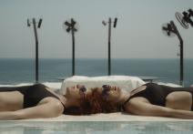 Dvě ženy leží u bazénu v černých plavkách ve filmu Je to ve hvězdách.